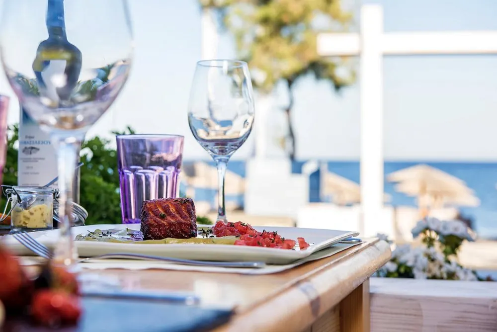 Ποτήρια κρασιού και πιάτο σε τραπέζι με θέα τη θάλασσα